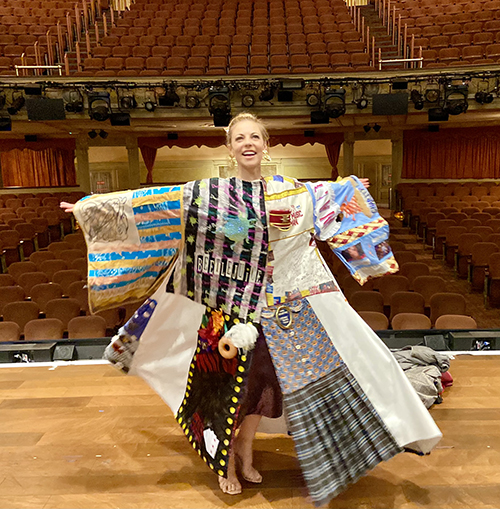 Kirsten Scott stands onstage, her back to the house seats, in the Legacy Robe.