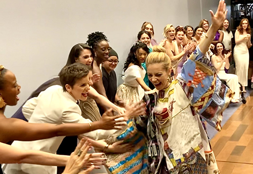 Scott looks excited onstage, her arms outstretched as the people nearest to her reach out to touch her hand.